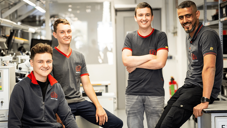 Group picture of 4 trainees in production at Micro-Hybrid in Hermsdorf
