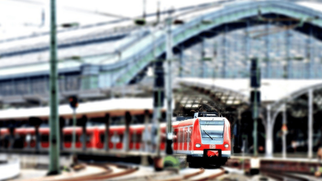 A red train of the company Deutsche Bahn drives out of a large roofed station
