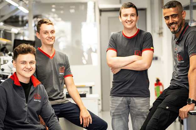 Group picture of 4 trainees in production at Micro-Hybrid in Hermsdorf