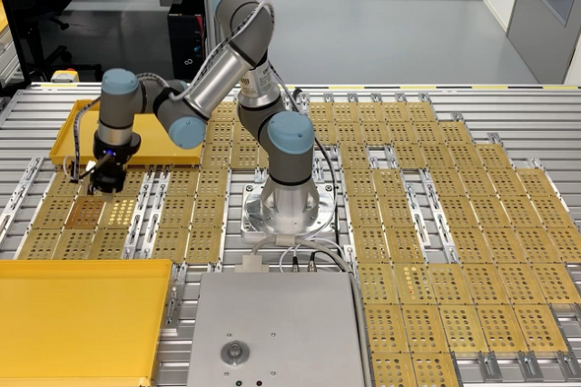 Roboterarm Cobot UR3e nimmt IR Strahler und platziert diese in einer Messvorrichtung