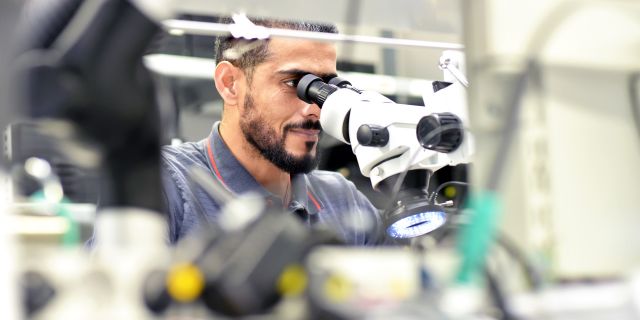 Employees at the microscope during soldering assembly